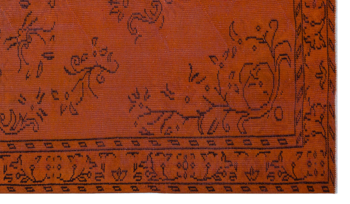 Rust-colored flatweave rug with a black linear floral pattern and a geometric border.