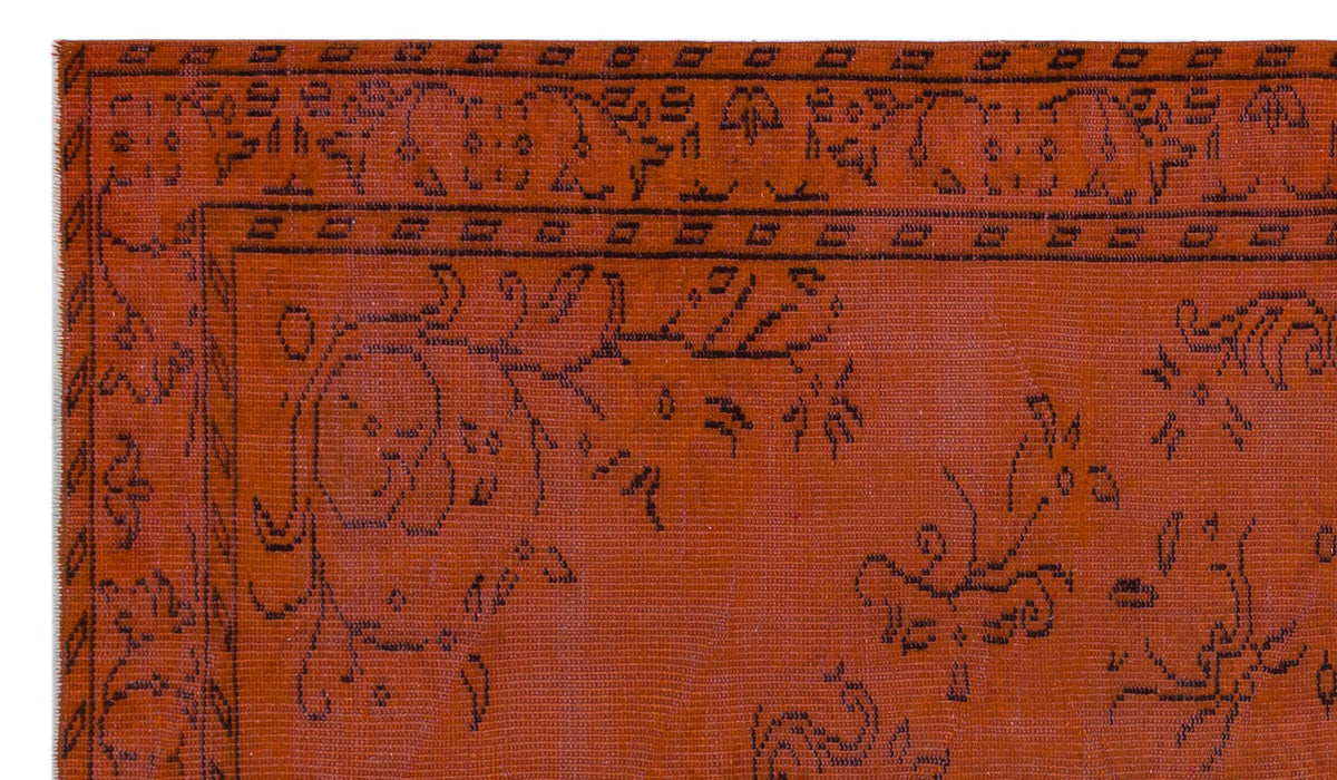Rust-colored rug with a black linear floral pattern and a geometric border.