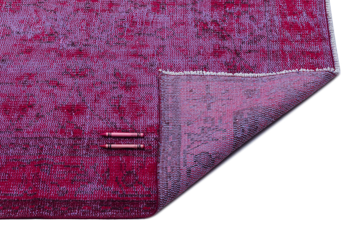Magenta and violet distressed-pattern rug with a folded corner revealing the woven backing, on a white background.