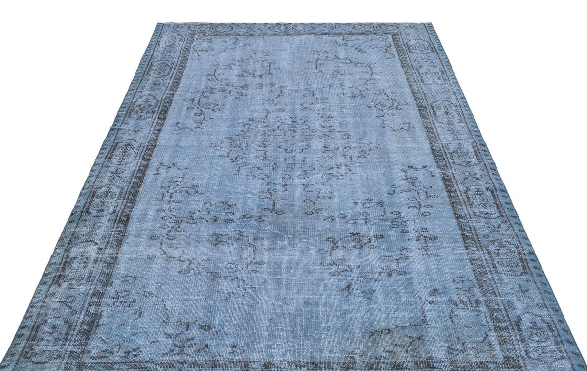 Light blue distressed rug with a dark grey traditional floral medallion and border pattern on a white background.