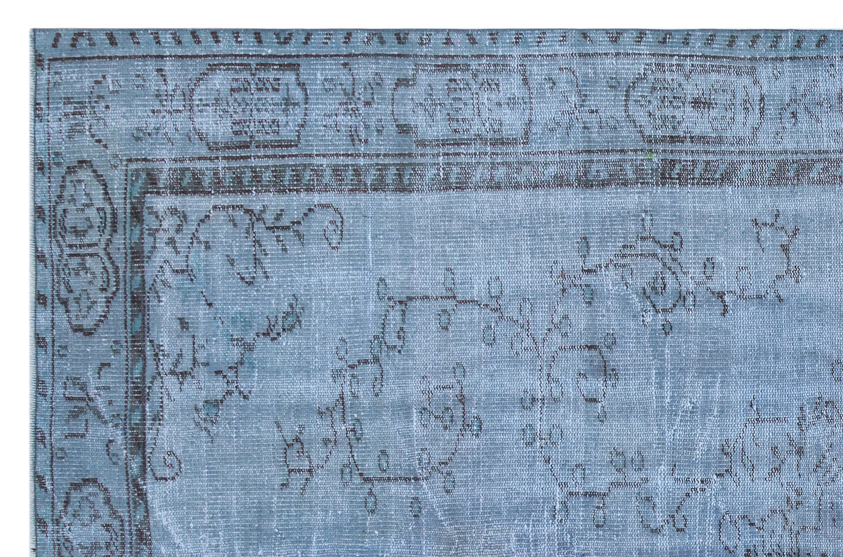 Distressed light blue rug with a dark grey floral vine pattern and a traditional geometric border.