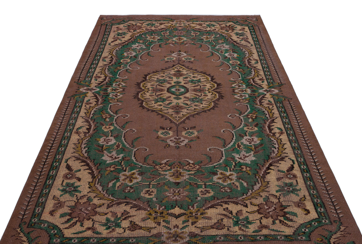 Brown traditional rug with a central floral medallion and green and beige ornate border patterns on a white background.