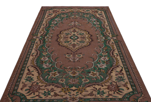 Load image 1 in gallery view. Brown traditional rug with a central floral medallion and green and beige ornate border patterns on a white background.