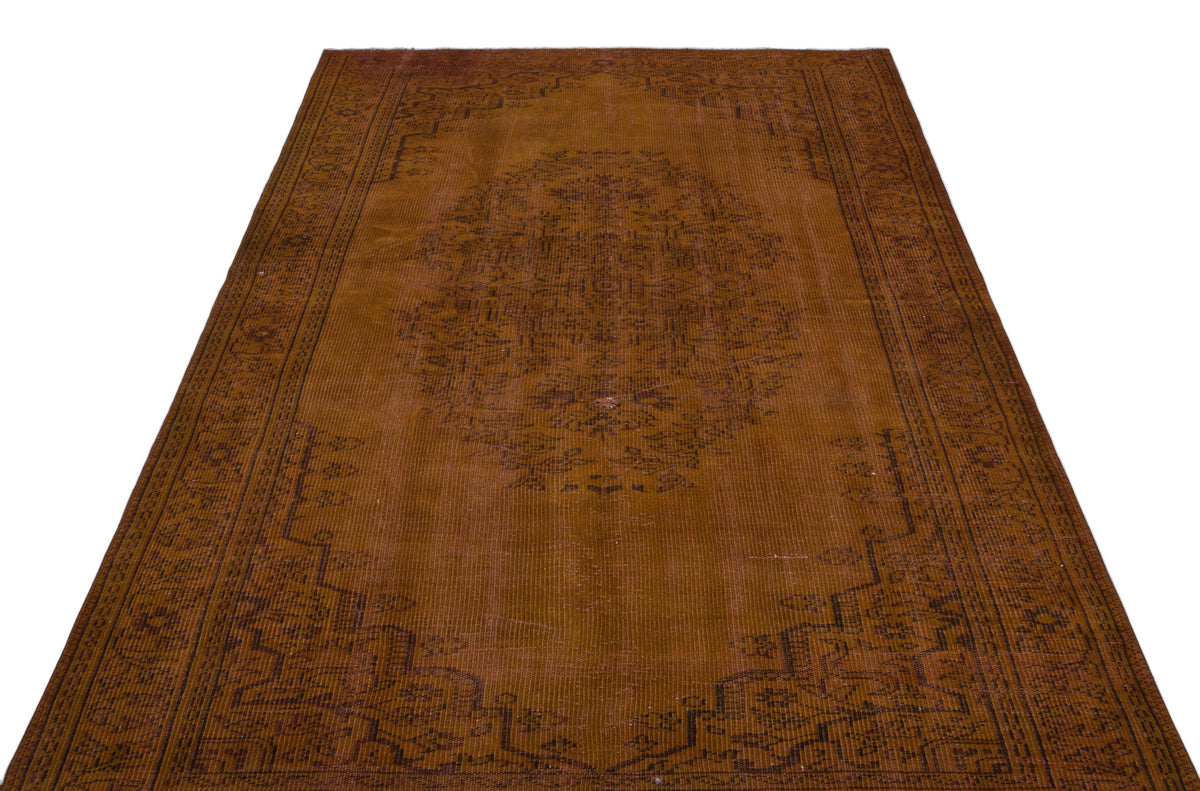 Distressed tobacco-brown rug with a dark central medallion and geometric border pattern on a white background.