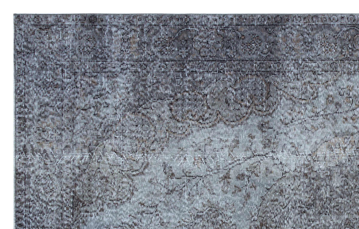 Grey and charcoal distressed rug with a faded traditional floral medallion pattern.