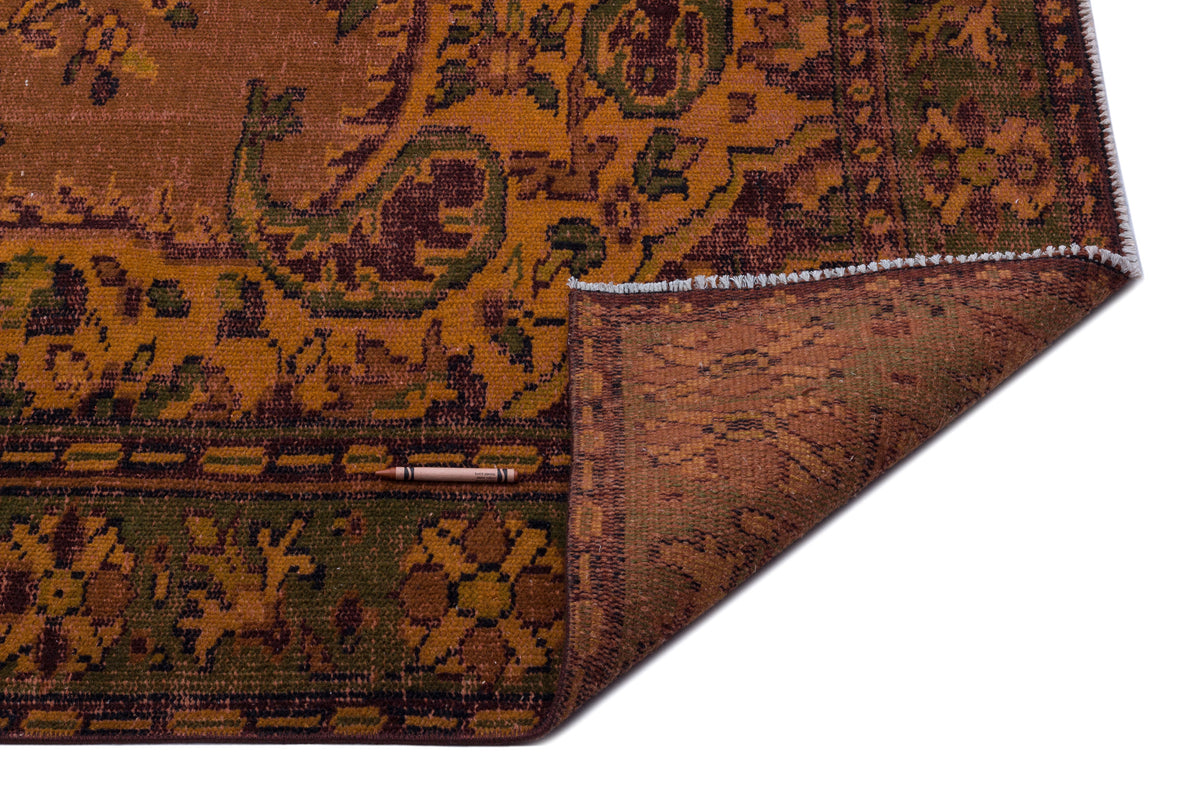 Rust, olive, and dark brown traditional patterned rug with a folded corner revealing the textured underside.