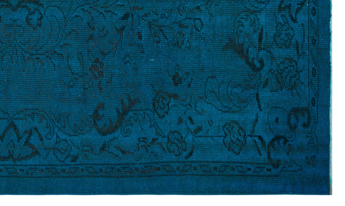 Teal rug with a black floral pattern and a geometric border.