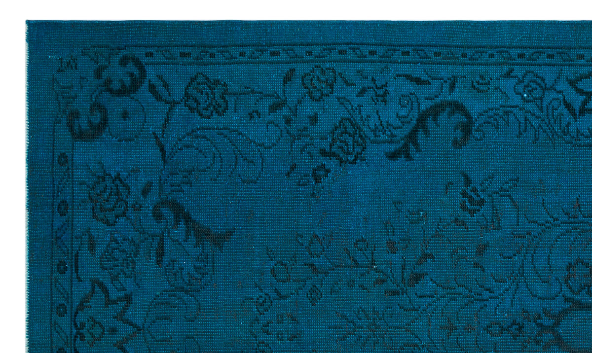 Teal rug with a black floral medallion pattern and a geometric border.