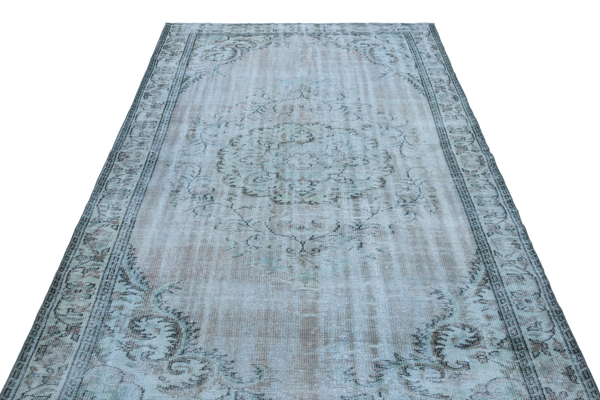 Light blue and grey distressed vintage-style rug with a central floral medallion and ornate border.