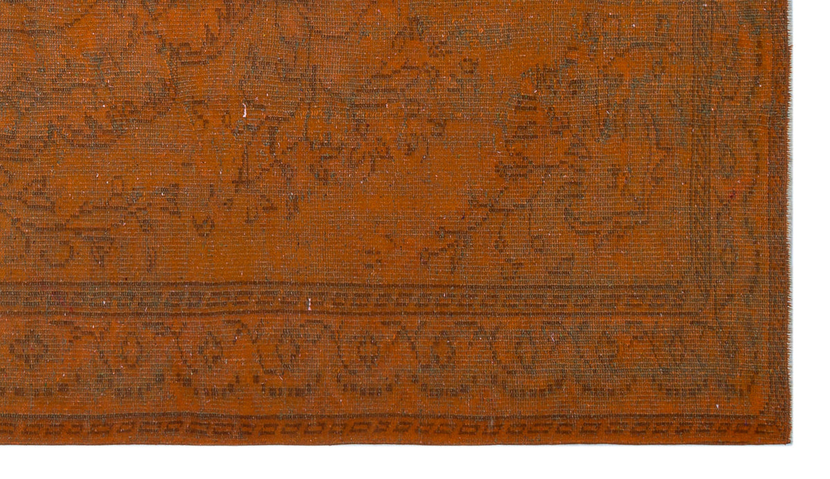 Burnt orange vintage-style rug with a faded, dark brown traditional floral medallion pattern and a decorative border.