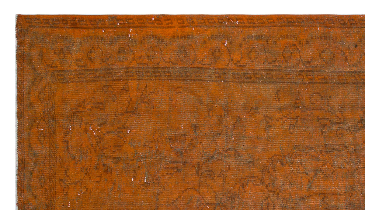 Burnt orange vintage-style rug with a faded, dark brown floral border and central medallion pattern.