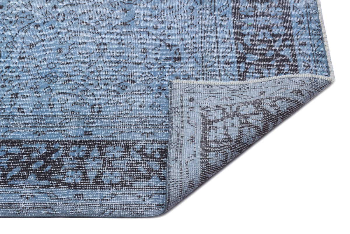 Blue and charcoal grey distressed rug with a traditional medallion pattern, shown with a corner folded over.