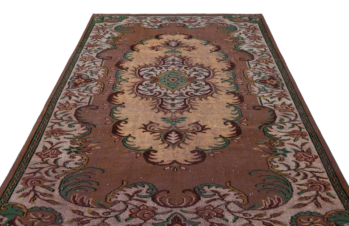 Brown, tan, and green traditional area rug with a central floral medallion and ornate border pattern on a white background.