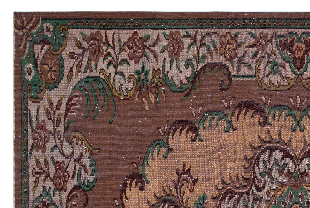 Brown traditional rug with a green and tan floral medallion pattern and a decorative border.