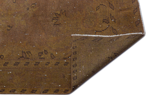 Load image 1 in gallery view. Distressed brown rug with a faded geometric pattern and a folded corner showing the woven backing.
