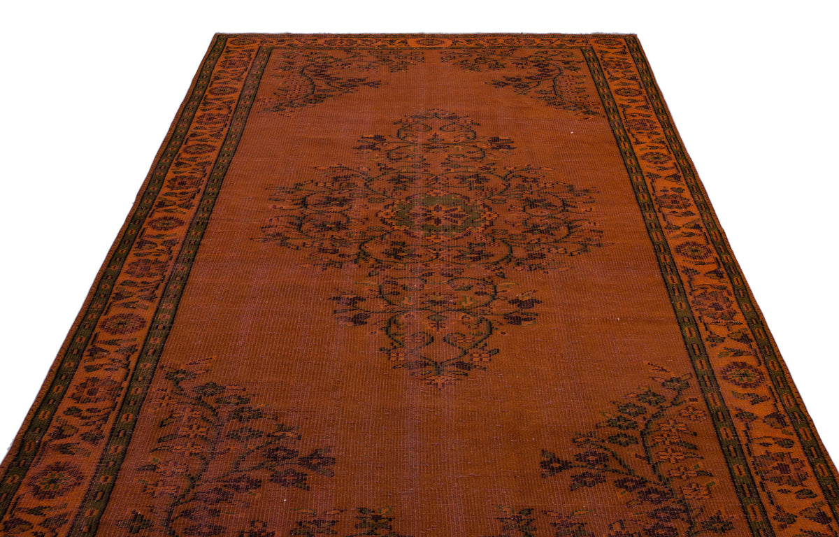 Rust-colored rug with a central dark floral medallion and a decorative border on a white background.