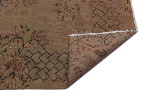 Load image 1 in gallery view. Brown vintage-style rug with a faded floral and geometric pattern, featuring a folded corner showing the underside.