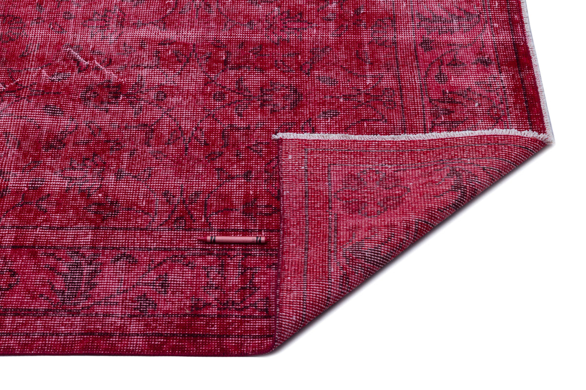 Deep red rug with a distressed traditional pattern and a folded corner, isolated on a white background.