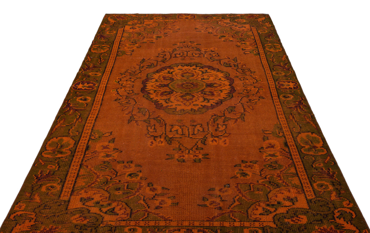 Rust-orange traditional rug with a central floral medallion and dark green border patterns on a white background.