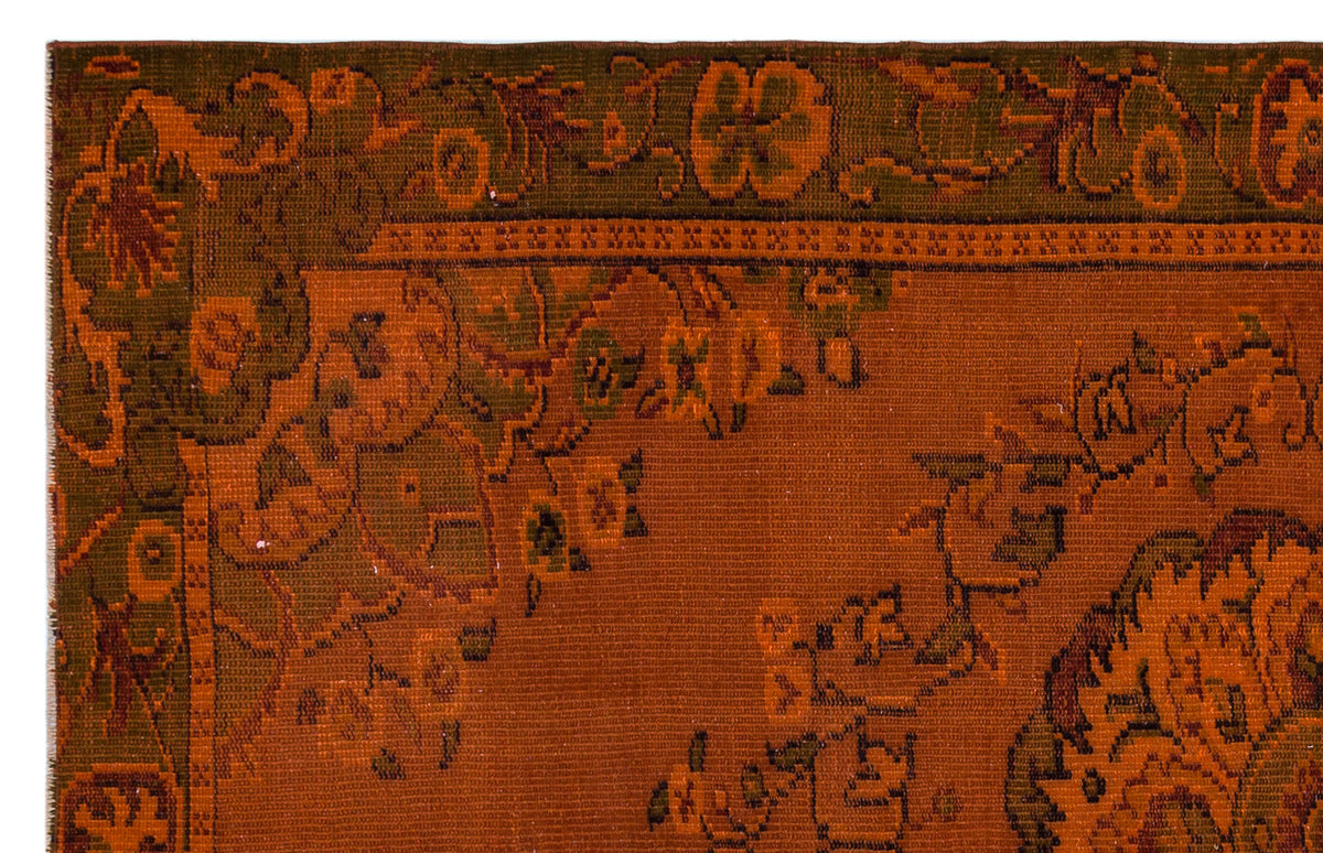 Rust orange and olive green rug with a traditional floral border and intricate botanical motifs.