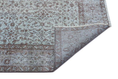 Load image 1 in gallery view. Light blue and brown distressed rug with a traditional floral pattern, shown with a corner folded to reveal the backing.