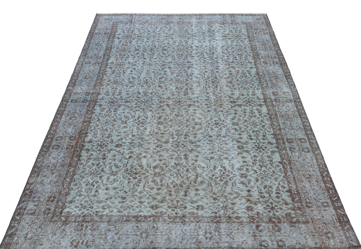 Light blue and brown distressed rug with an intricate floral medallion pattern and a wide decorative border.