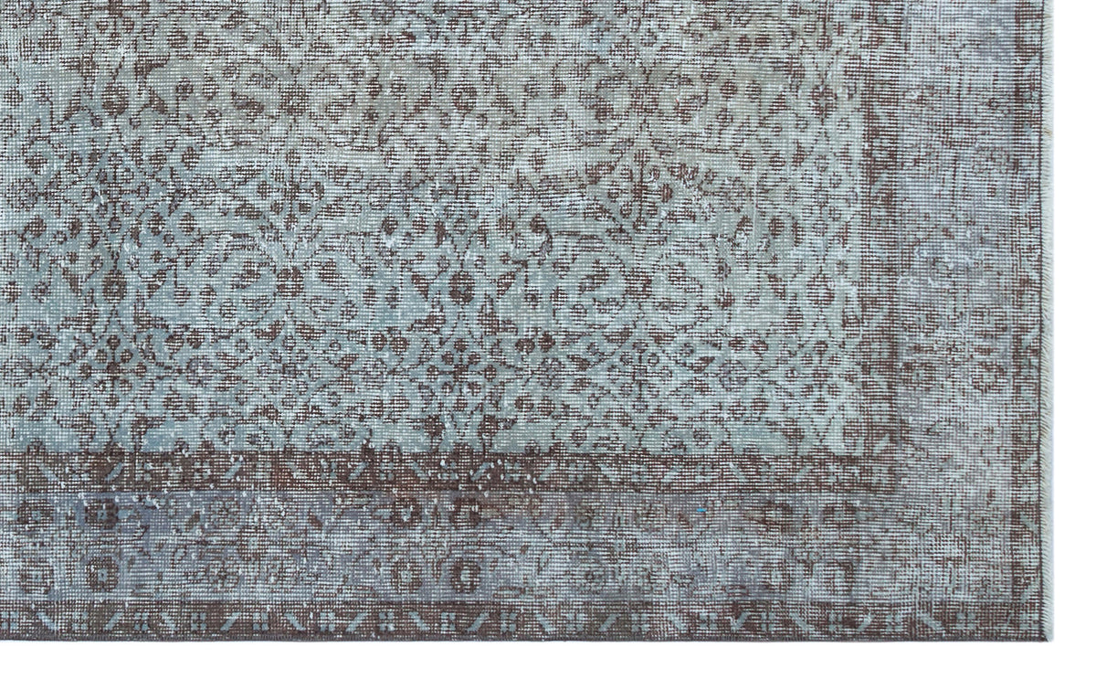 Distressed blue and brown rug with a traditional floral medallion pattern and a wide decorative border.