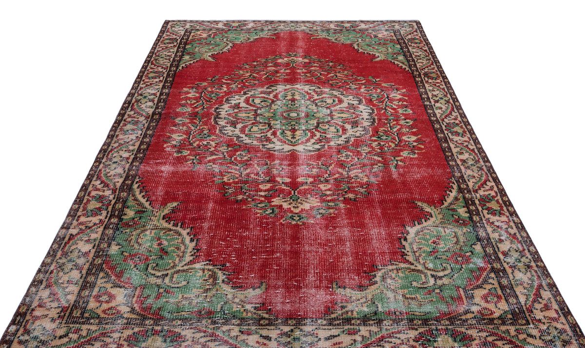 Distressed red Persian-style rug with a central cream and green floral medallion and ornate border.