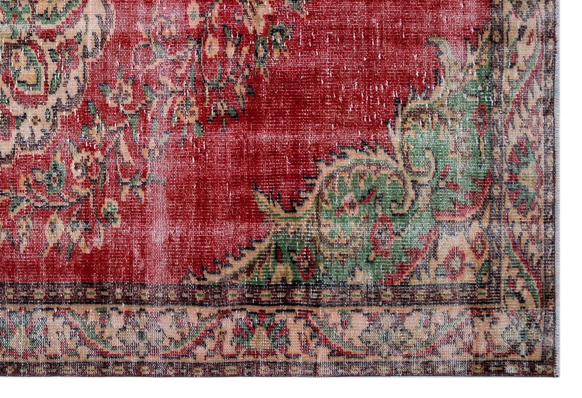 Distressed red rug with green and beige floral medallion patterns and a decorative border.