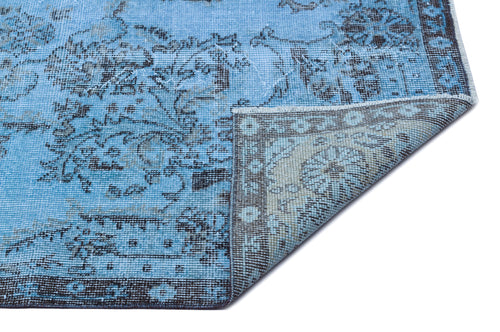 Load image 1 in gallery view. Bright blue distressed rug with a dark grey traditional floral pattern and a folded corner showing the backing.