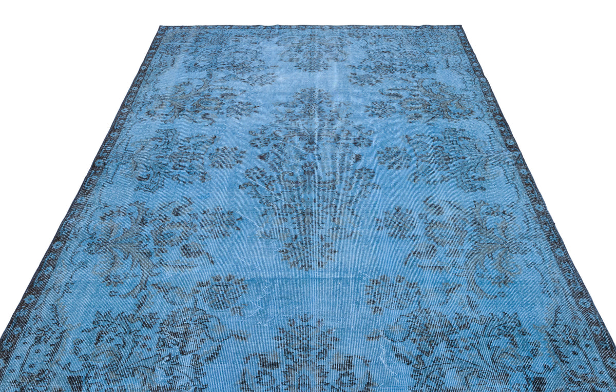 Bright blue distressed rug with a dark charcoal floral medallion pattern on a white background.