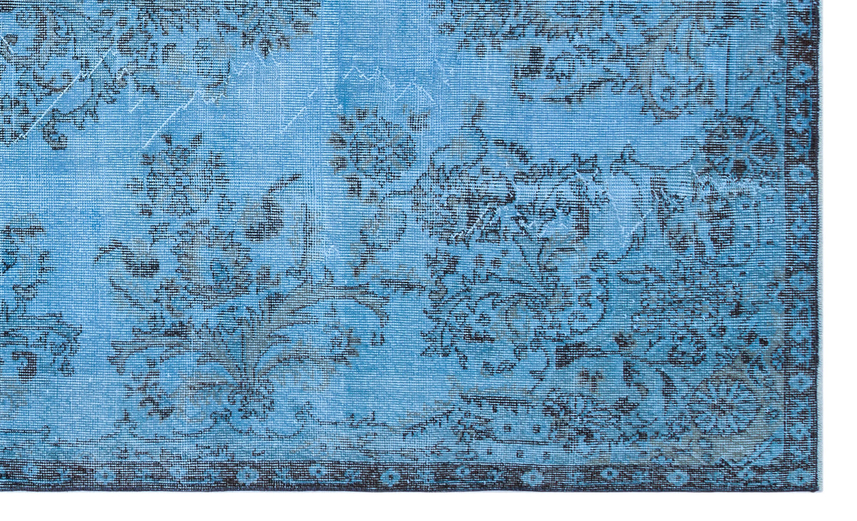 Bright blue rug with a distressed black floral pattern and a dark decorative border.