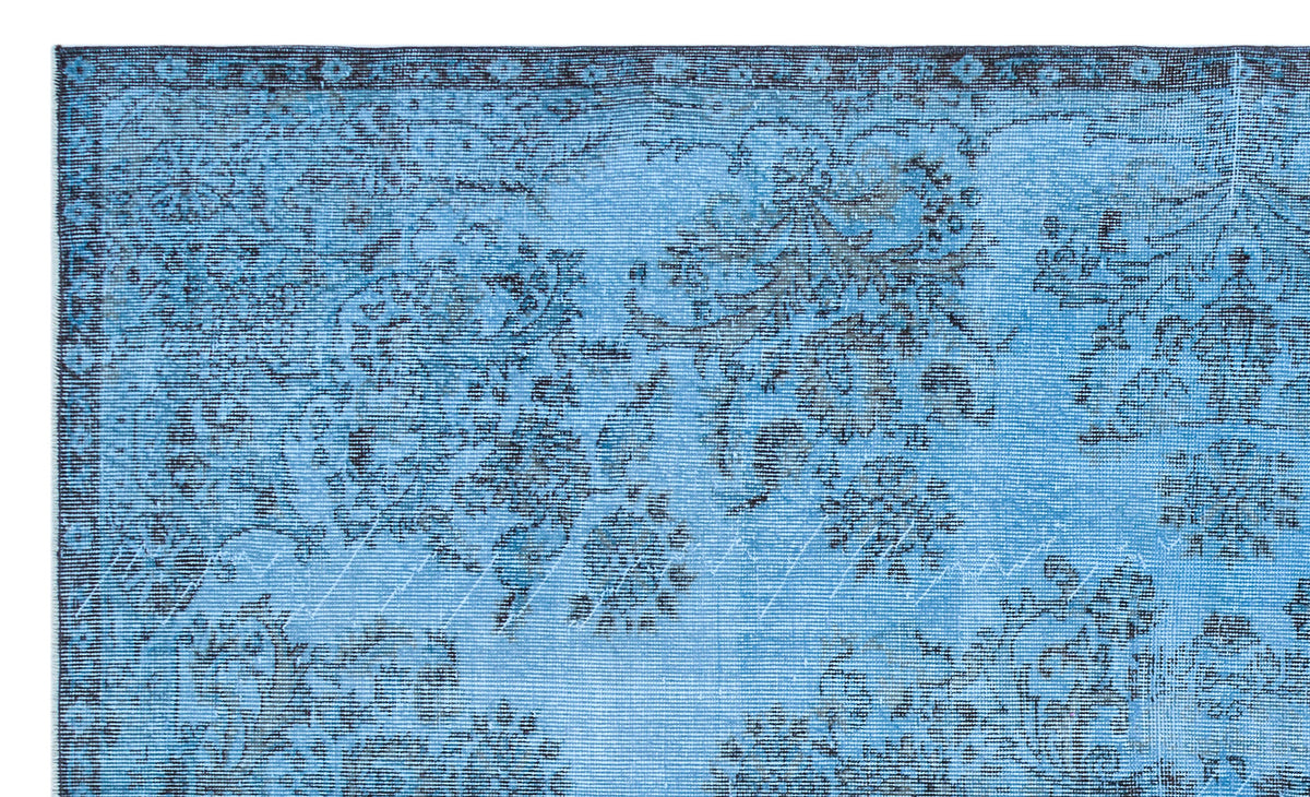 Bright blue rug with a distressed black floral medallion pattern and a decorative border.