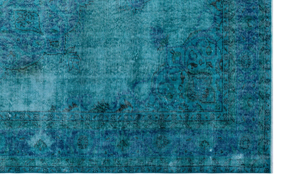 Teal and blue distressed rug with a traditional floral medallion border and faded intricate patterns.