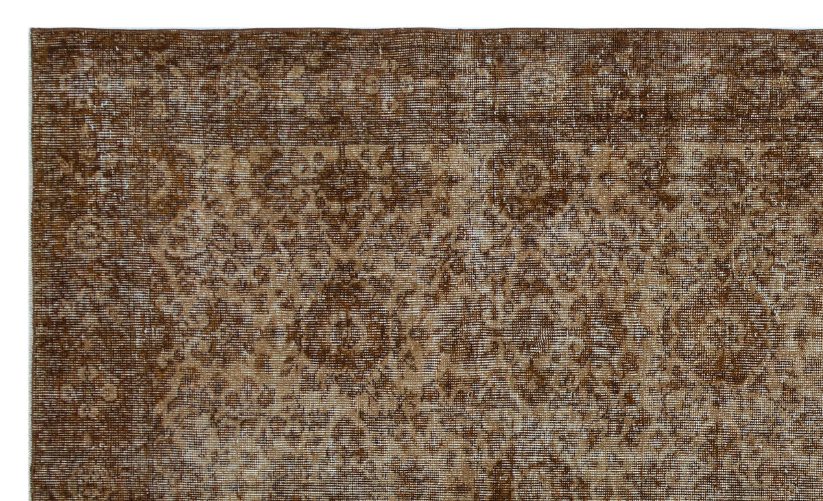 Dark brown and tan distressed rug with a traditional floral medallion pattern and a wide decorative border.