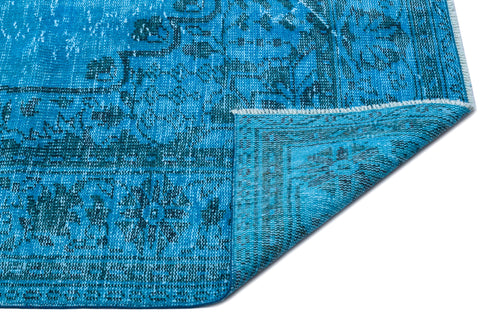 Load image 1 in gallery view. Bright blue distressed rug with a dark teal traditional floral medallion pattern, shown with a corner folded over.