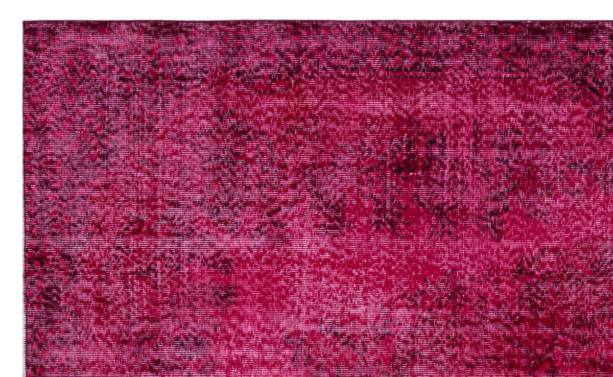 Magenta and black distressed overdyed rug with a faint, traditional floral medallion pattern.