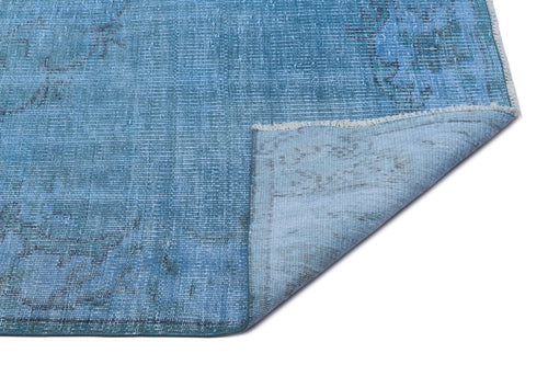Load image 1 in gallery view. Distressed blue area rug with a faded traditional medallion pattern and a folded corner showing the backing.