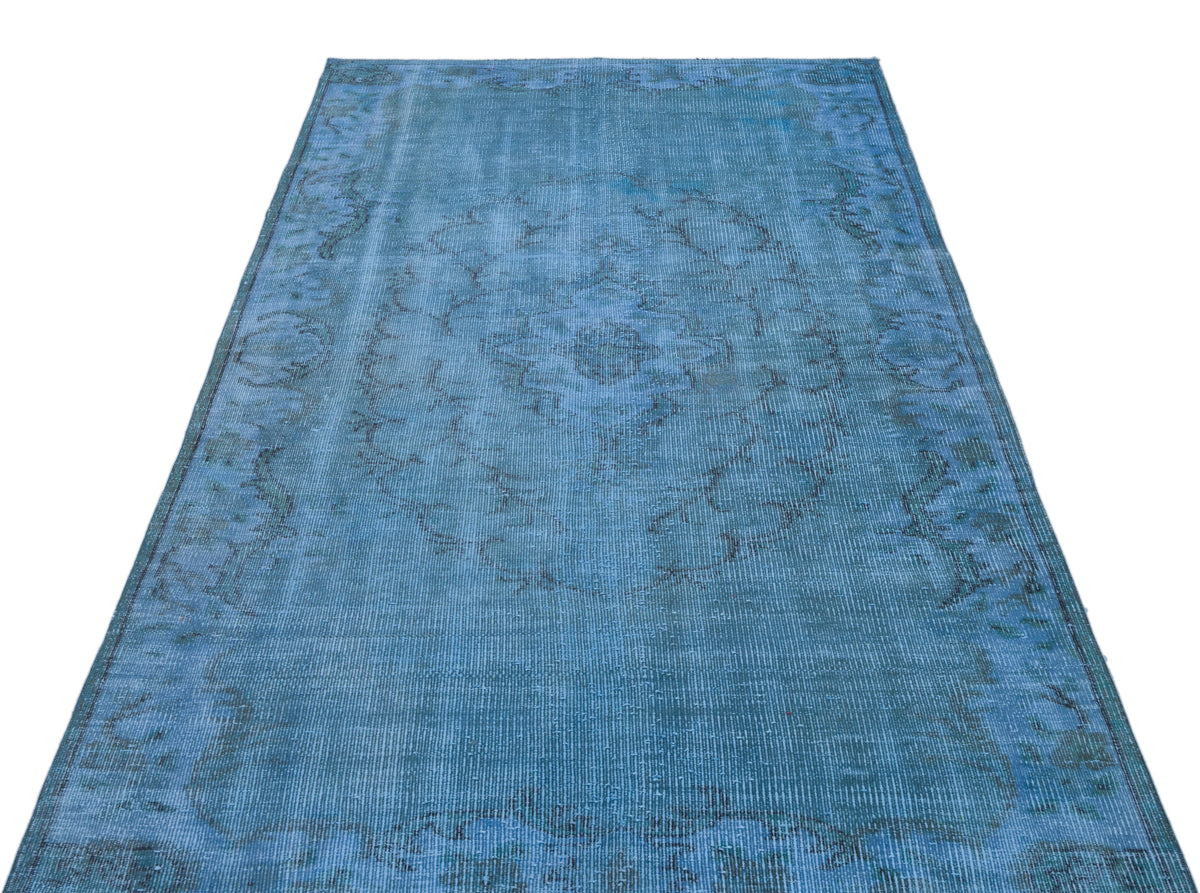 Distressed blue rug with a faded central medallion and ornate border pattern on a white background.