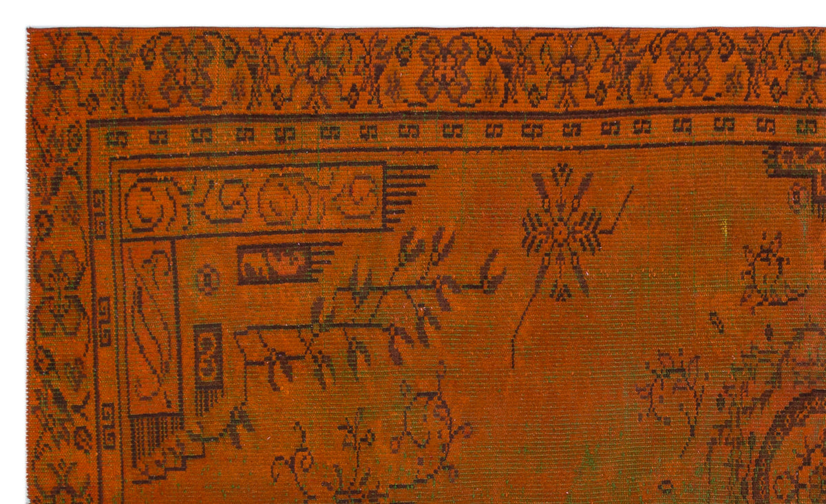 Burnt orange rug with a dark brown traditional border and scattered geometric and floral motifs.