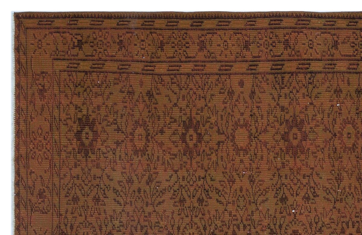 Rust and brown traditional rug with a repeating floral medallion pattern and a geometric border.