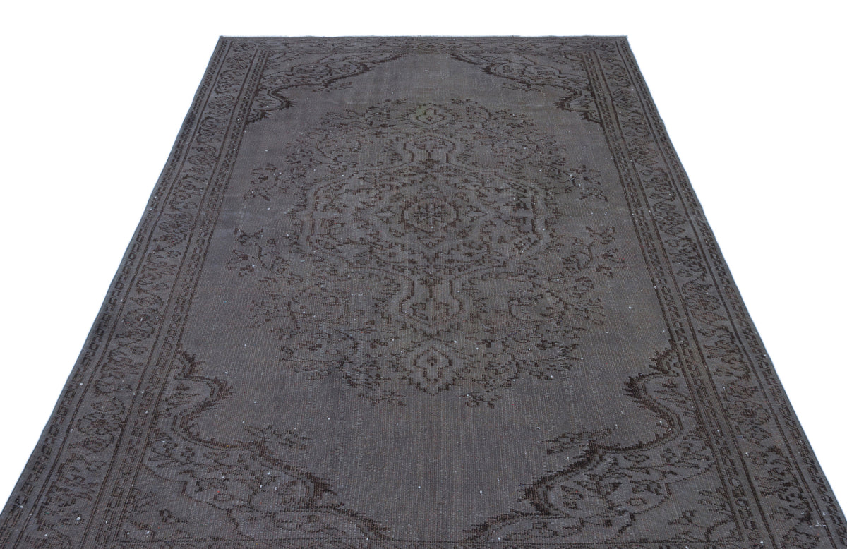 Dark charcoal and brown distressed rug with a traditional central medallion and ornate border pattern.
