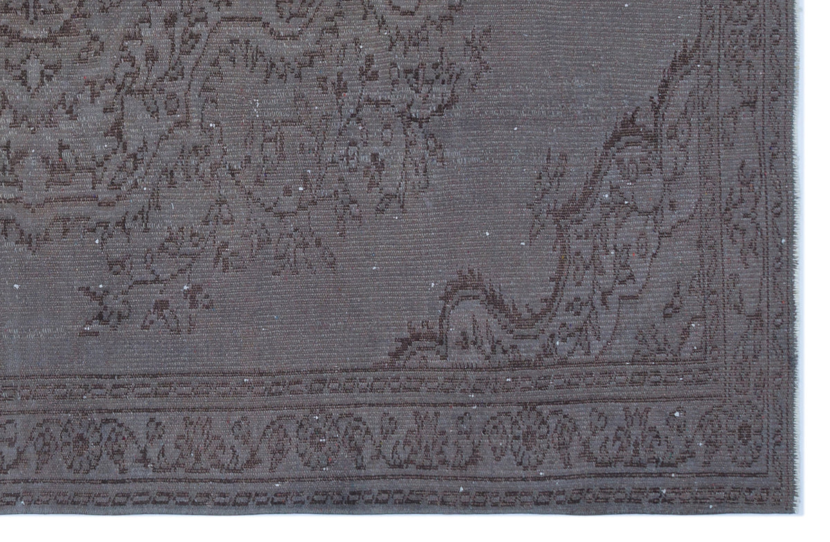 Dark charcoal grey rug with a faded, traditional floral medallion pattern and a geometric border.
