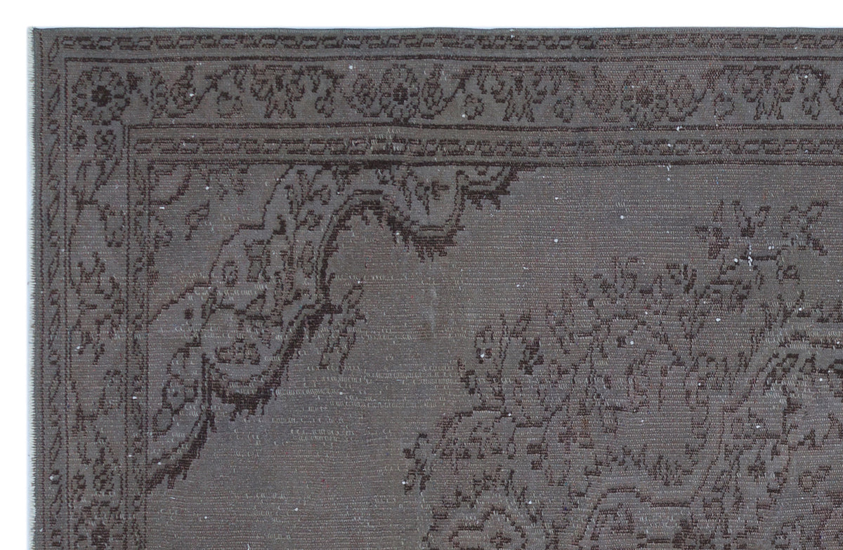 Dark brown distressed rug with a traditional floral medallion border and intricate ornamental patterns.