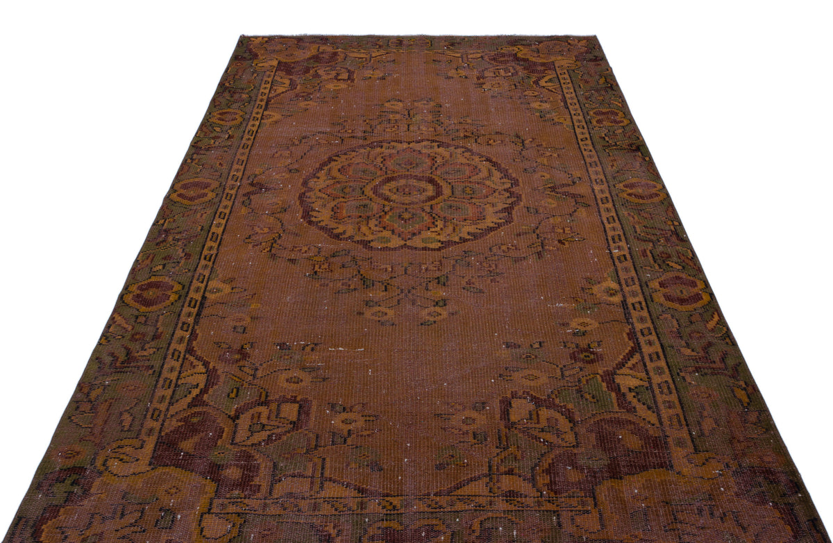 Distressed rust-brown vintage rug with a central floral medallion and ornate border patterns on a white background.