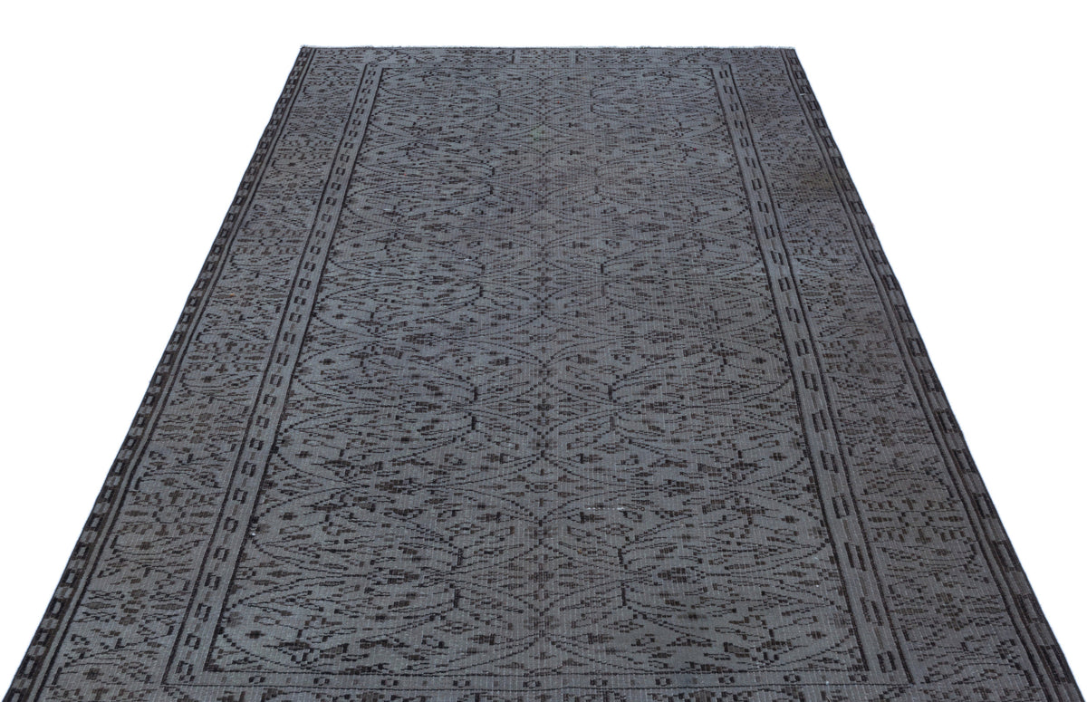 Charcoal grey rug with a repeating geometric lattice pattern and a linear border on a white background.