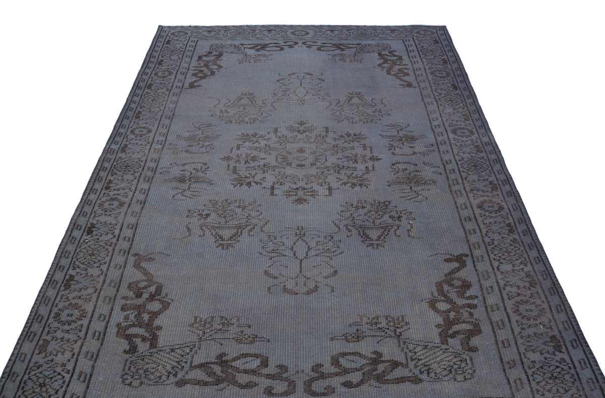 Grey and brown distressed rug with a central floral medallion and ornate border pattern on a white background.