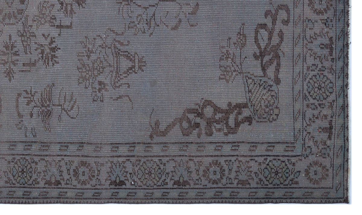 Charcoal grey rug with a faded traditional floral medallion pattern and a detailed geometric border.