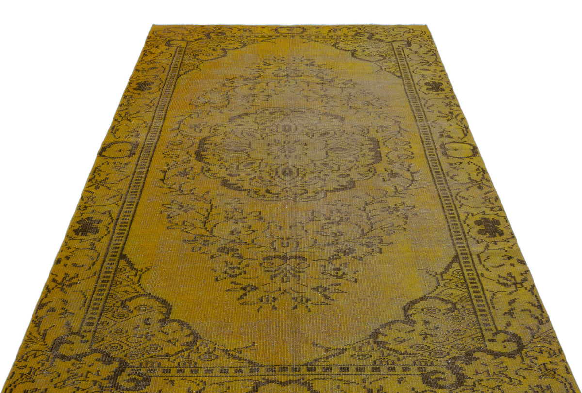 Mustard yellow and brown vintage-style rug with a central floral medallion and ornate border on a white background.
