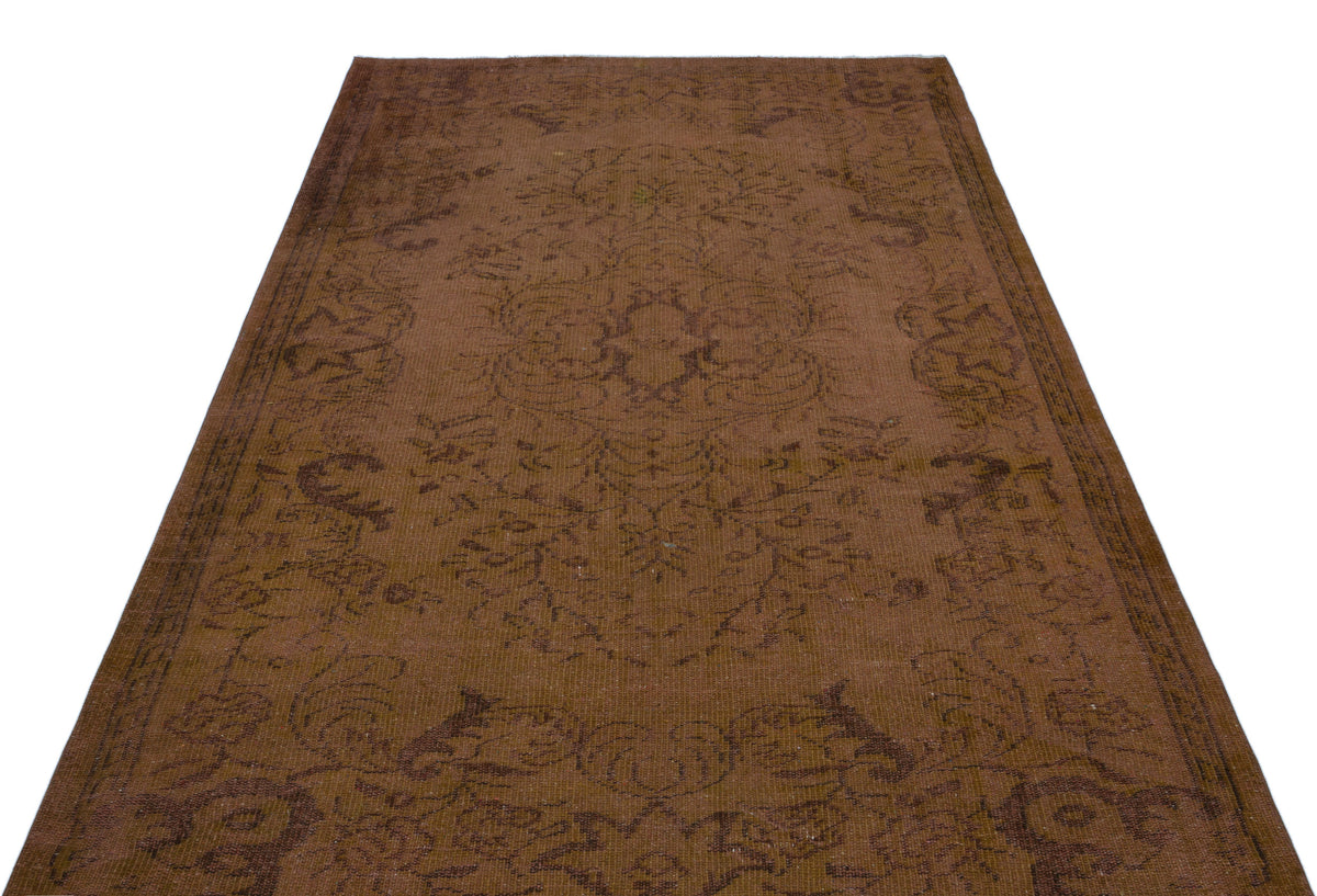 Monochromatic brown vintage-style rug with a faint, distressed floral medallion pattern.